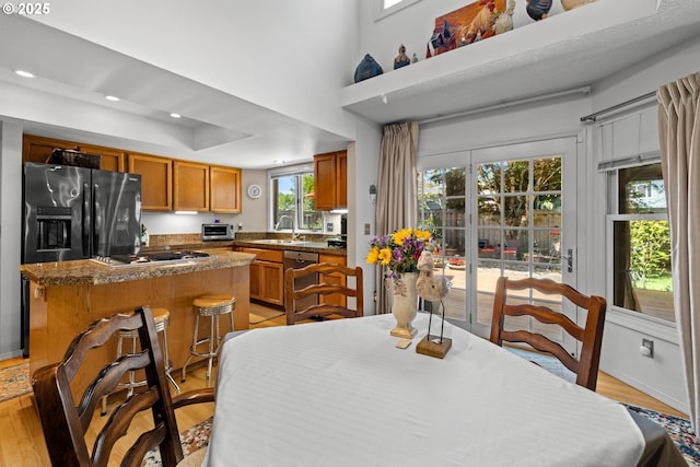 16165 NW Blueridge Dr, Beaverton, OR 97006 - kitchen featuring appliances with stainless steel finishes, brown cabinetry, light wood-style flooring, a kitchen island, and recessed lighting