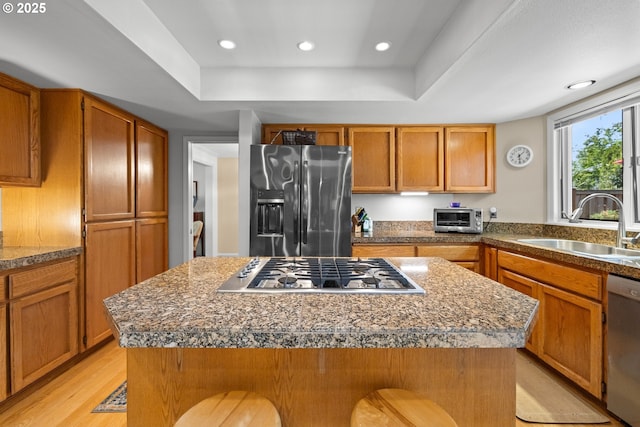 16165 NW Blueridge Dr, Beaverton, OR 97006 - kitchen with appliances with stainless steel finishes, a center island, a raised ceiling, light wood-style floors, and a kitchen bar