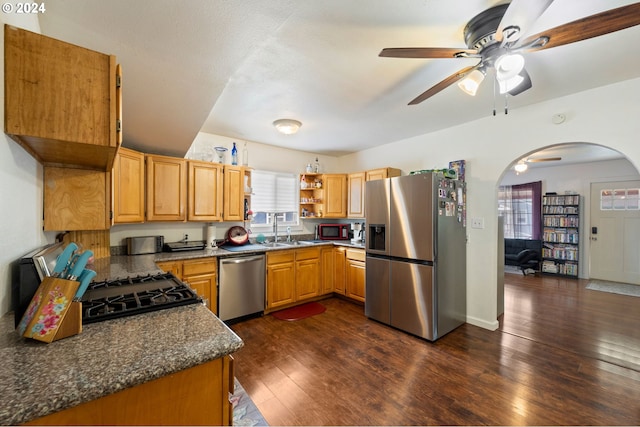 kitchen featuring dark wood-type flooring, ceiling fan, appliances with stainless steel finishes, and dark stone counters