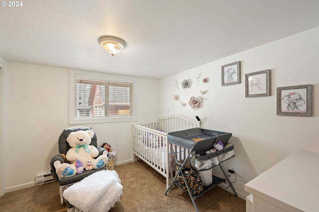 bedroom with carpet floors, baseboard heating, a textured ceiling, and a crib