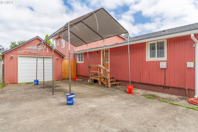 back of house with a garage, an outdoor structure, and a carport