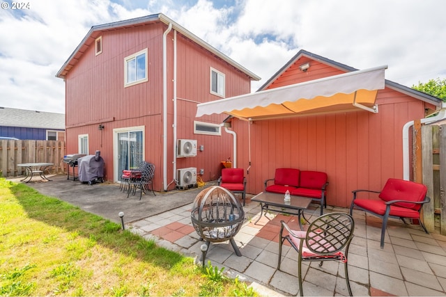 rear view of house featuring a lawn, ac unit, an outdoor living space with a fire pit, and a patio area