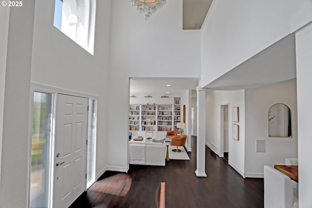 entrance foyer featuring a high ceiling, dark wood finished floors, baseboards, and ornate columns