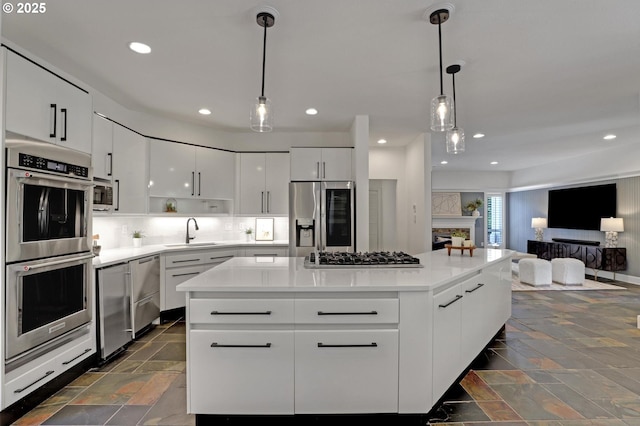 kitchen with stainless steel appliances, a sink, stone tile flooring, modern cabinets, and white cabinetry