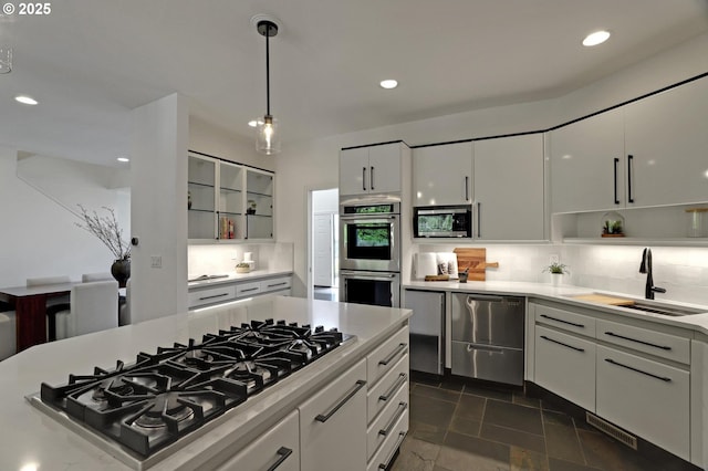 kitchen with appliances with stainless steel finishes, a sink, backsplash, recessed lighting, and light countertops