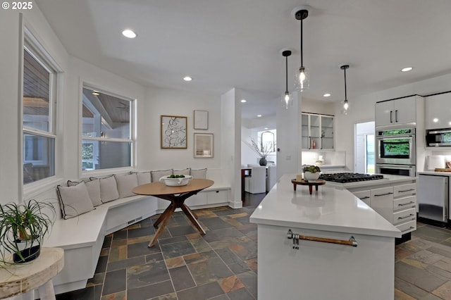 kitchen with appliances with stainless steel finishes, stone tile flooring, recessed lighting, a kitchen island, and white cabinets