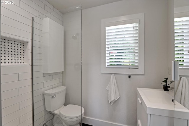 full bathroom featuring plenty of natural light, toilet, vanity, and tiled shower