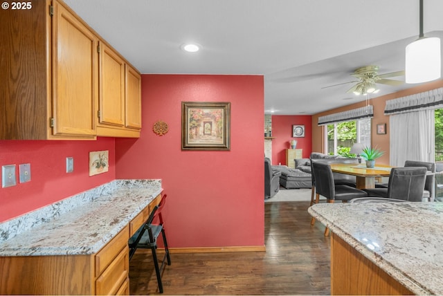 180 NE 29th Dr, Gresham, OR 97030 - kitchen with dark wood-style flooring, a ceiling fan, open floor plan, light stone countertops, and baseboards