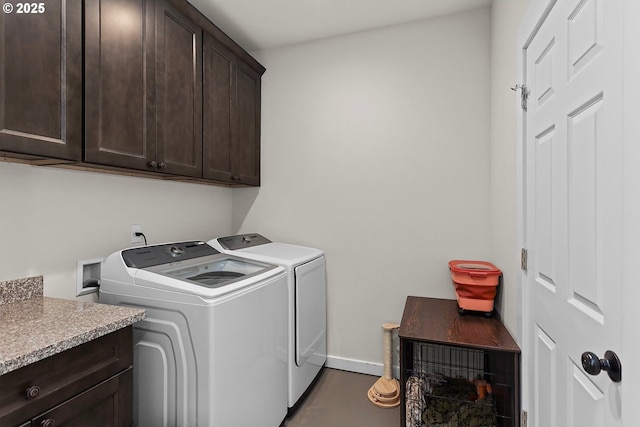 clothes washing area featuring separate washer and dryer, cabinet space, and baseboards