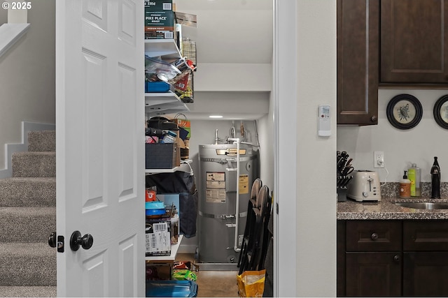 storage area featuring strapped water heater and a sink