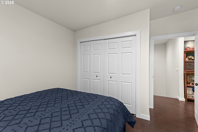 unfurnished bedroom featuring dark wood-type flooring, a closet, and baseboards