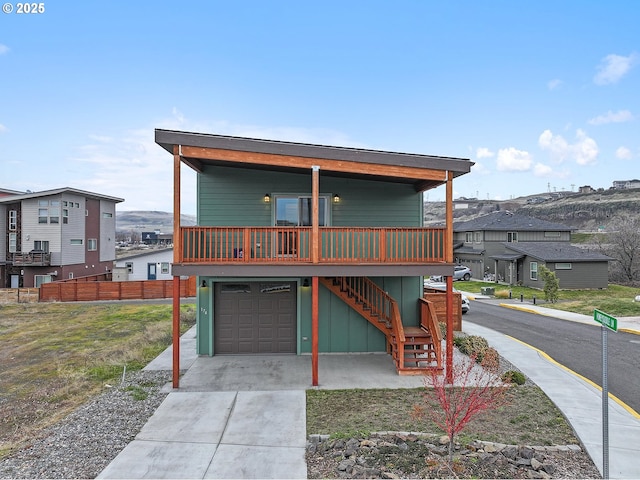 view of front facade featuring a garage, a residential view, driveway, and stairs