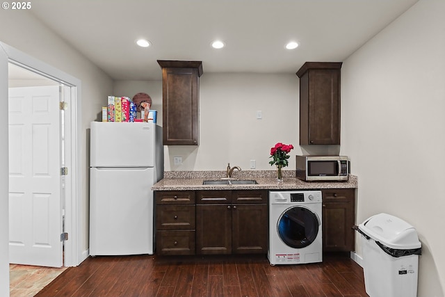 kitchen with washer / clothes dryer, stainless steel microwave, freestanding refrigerator, a sink, and dark brown cabinets