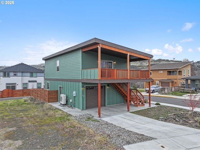 view of front of home featuring an attached garage, board and batten siding, a balcony, driveway, and stairs