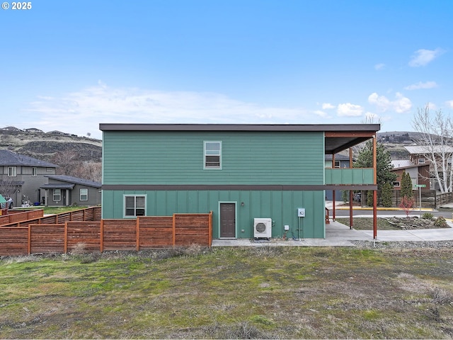 back of property with ac unit, fence, and a mountain view