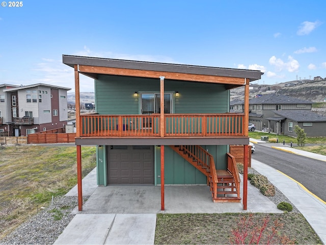 view of front of property featuring a residential view, concrete driveway, stairway, and an attached garage