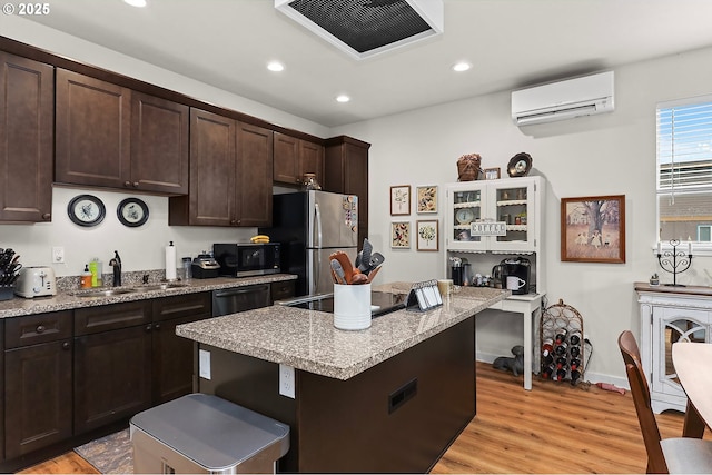 kitchen featuring black appliances, dark brown cabinets, a kitchen island, and visible vents