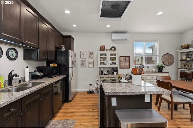 kitchen featuring visible vents, appliances with stainless steel finishes, an AC wall unit, a sink, and dark brown cabinetry