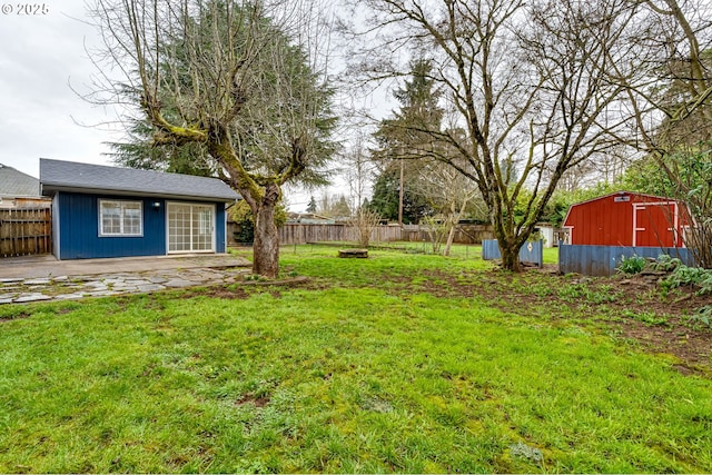 view of yard with an outbuilding, a patio, a storage unit, and a fenced backyard