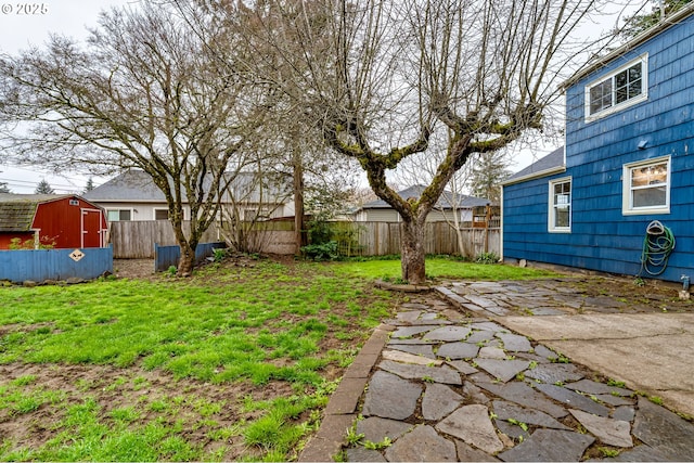 view of yard with a storage unit, an outdoor structure, a fenced backyard, and a patio area