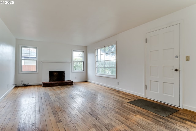 unfurnished living room with baseboards, a brick fireplace, and hardwood / wood-style floors