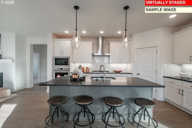 22987 Bland Cir, West Linn, OR 97068 - kitchen with stainless steel appliances, wall chimney range hood, dark countertops, a sink, and a breakfast bar area