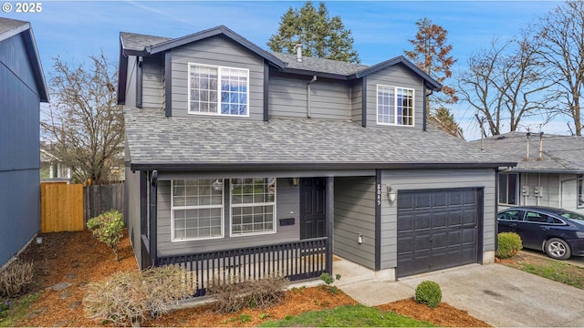 traditional home with concrete driveway, fence, and a shingled roof