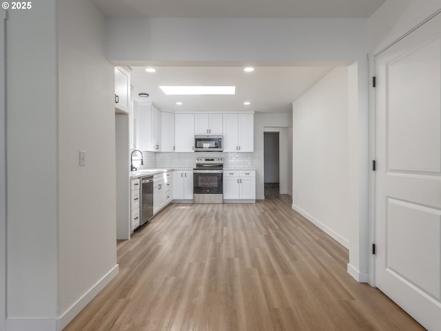 13928 SE Rhone St, Portland, OR 97236 - kitchen with stainless steel appliances, light wood-type flooring, backsplash, white cabinets, and recessed lighting