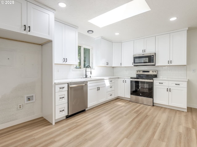 13928 SE Rhone St, Portland, OR 97236 - kitchen with stainless steel appliances, a sink, light wood-type flooring, a skylight, and tasteful backsplash