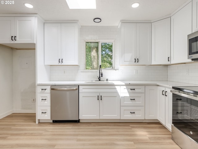 13928 SE Rhone St, Portland, OR 97236 - kitchen featuring appliances with stainless steel finishes, a sink, white cabinets, tasteful backsplash, and recessed lighting