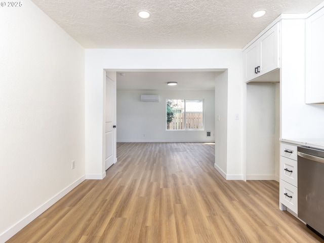 13928 SE Rhone St, Portland, OR 97236 - kitchen featuring a wall mounted air conditioner, stainless steel dishwasher, light wood finished floors, baseboards, and a textured ceiling