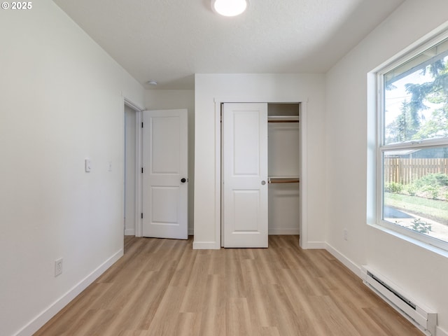 13928 SE Rhone St, Portland, OR 97236 - unfurnished bedroom featuring a baseboard radiator, light wood-style floors, multiple windows, and a closet