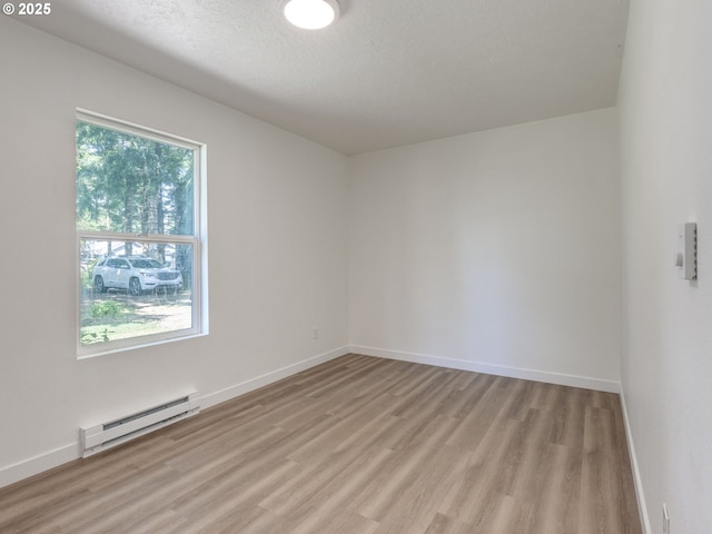 13928 SE Rhone St, Portland, OR 97236 - empty room with a baseboard heating unit, light wood-style flooring, and baseboards