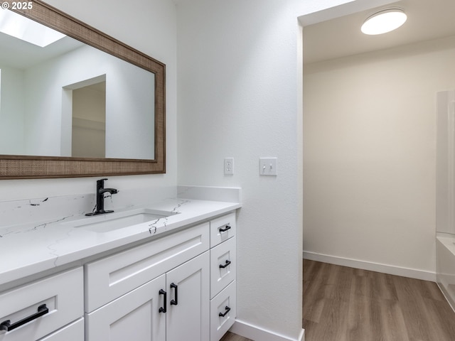 13928 SE Rhone St, Portland, OR 97236 - bathroom featuring wood finished floors, vanity, baseboards, and a skylight