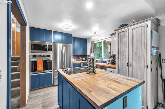 162 Monticello Dr, Longview, WA 98632 - kitchen featuring butcher block counters, appliances with stainless steel finishes, blue cabinetry, and a textured ceiling