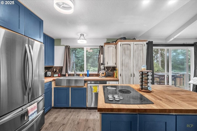 162 Monticello Dr, Longview, WA 98632 - kitchen featuring stainless steel appliances, wooden counters, blue cabinets, light wood-type flooring, and a textured ceiling