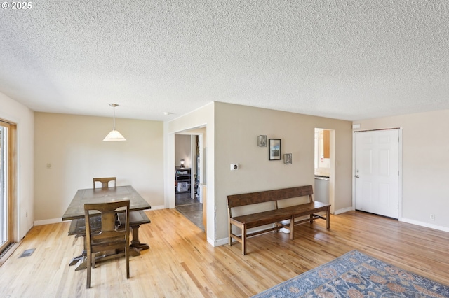 dining room with a textured ceiling, light wood finished floors, and baseboards