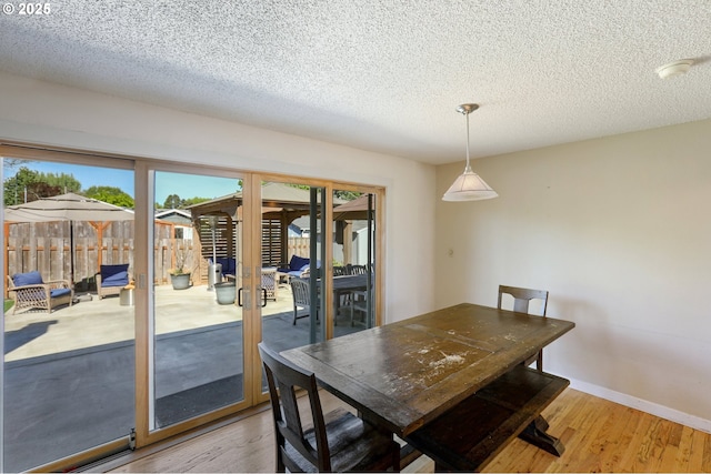 dining room with french doors, light wood-type flooring, healthy amount of natural light, and a textured ceiling