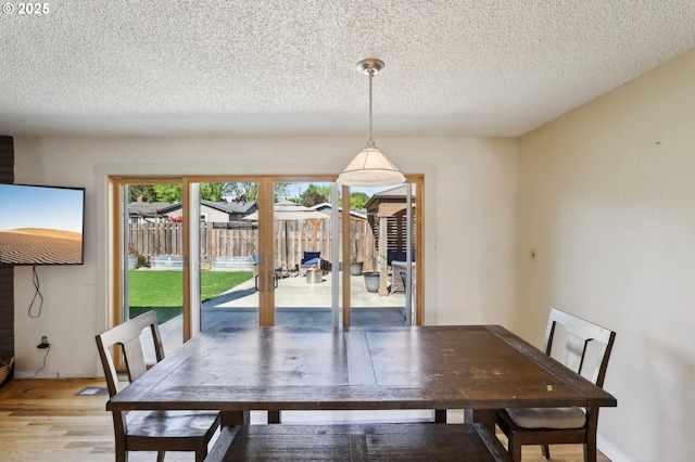 unfurnished dining area featuring a textured ceiling, french doors, and light wood-style floors