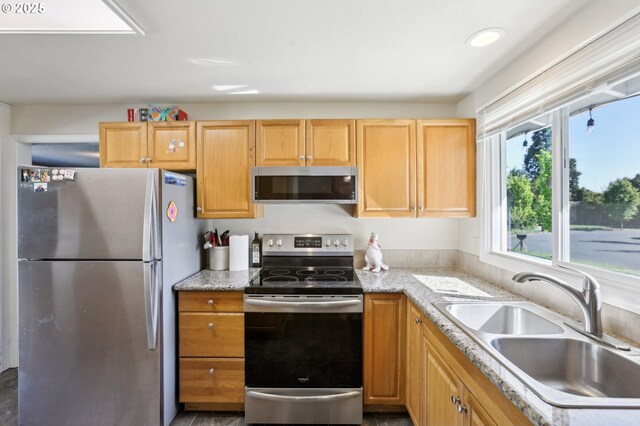 kitchen with stainless steel appliances, a sink, and light stone countertops