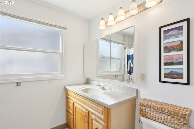bathroom with healthy amount of natural light, vanity, toilet, and curtained shower