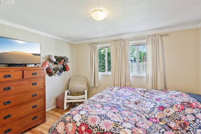 bedroom featuring light wood finished floors, ornamental molding, and a textured ceiling