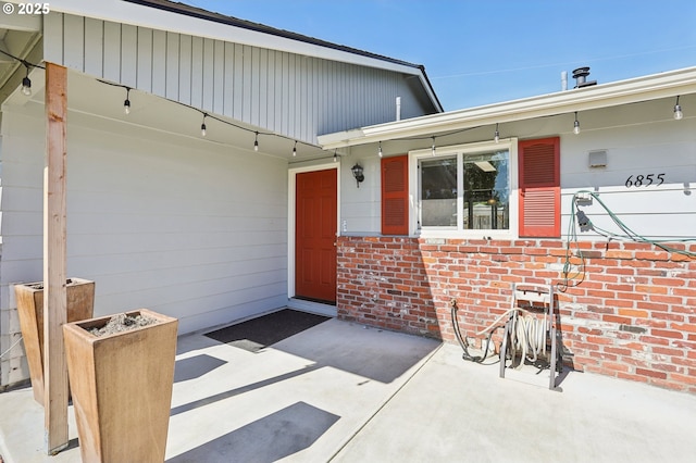 property entrance with brick siding and a patio area