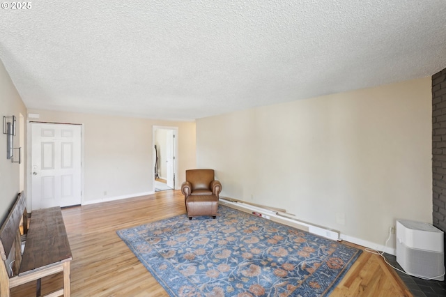 sitting room featuring wood finished floors, a textured ceiling, and baseboards