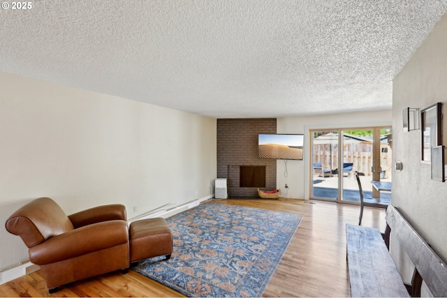 living area featuring a textured ceiling, wood finished floors, a fireplace, and a baseboard radiator