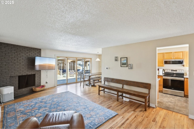 living area featuring a textured ceiling, light wood-style flooring, and a fireplace