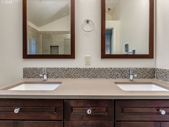 bathroom with decorative backsplash, a shower with door, vanity, and vaulted ceiling