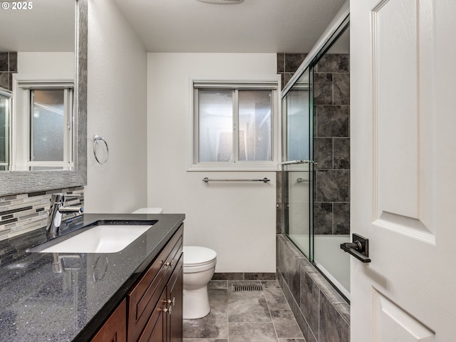 full bathroom with combined bath / shower with glass door, vanity, and toilet