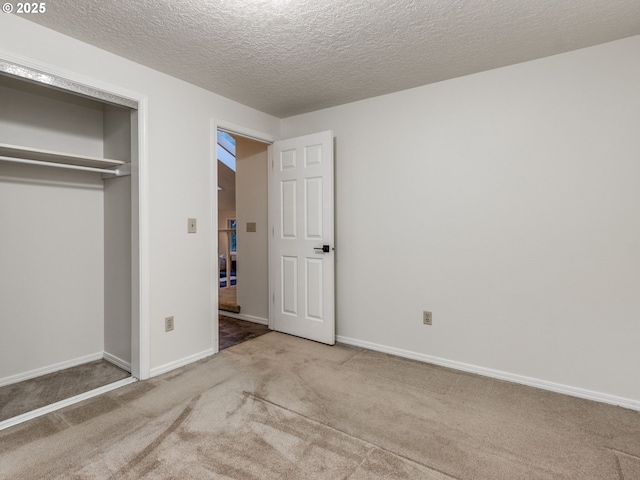 unfurnished bedroom with light colored carpet, a textured ceiling, and a closet