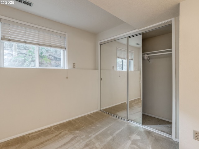 unfurnished bedroom with light carpet and a closet